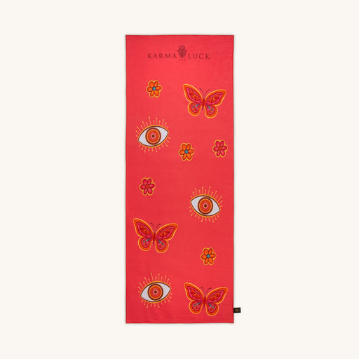 Red yoga mat with butterfly and eye designs on a white background